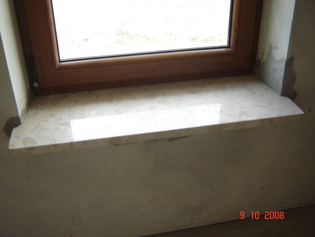 Jasny parapet pod oknem z brązową ramą